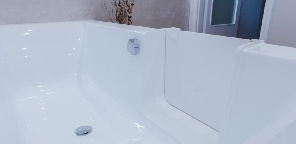 Moderne, geräumige Badewanne mit geöffneter, barrierearmer Tür, die einen einfachen und sicheren Zugang bietet. Der Fokus liegt auf der Tür und dem Badezimmerinterieur.